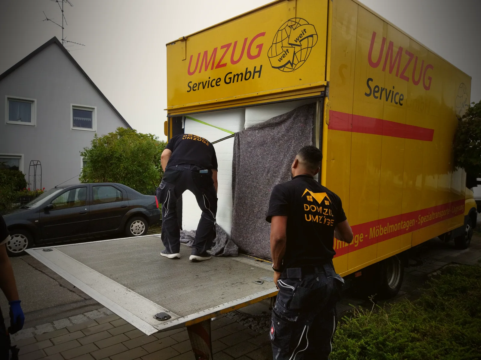 Zwei Mitarbeiter von Domizil Umzüge sichern Umzugsgut auf der Ladebordwand