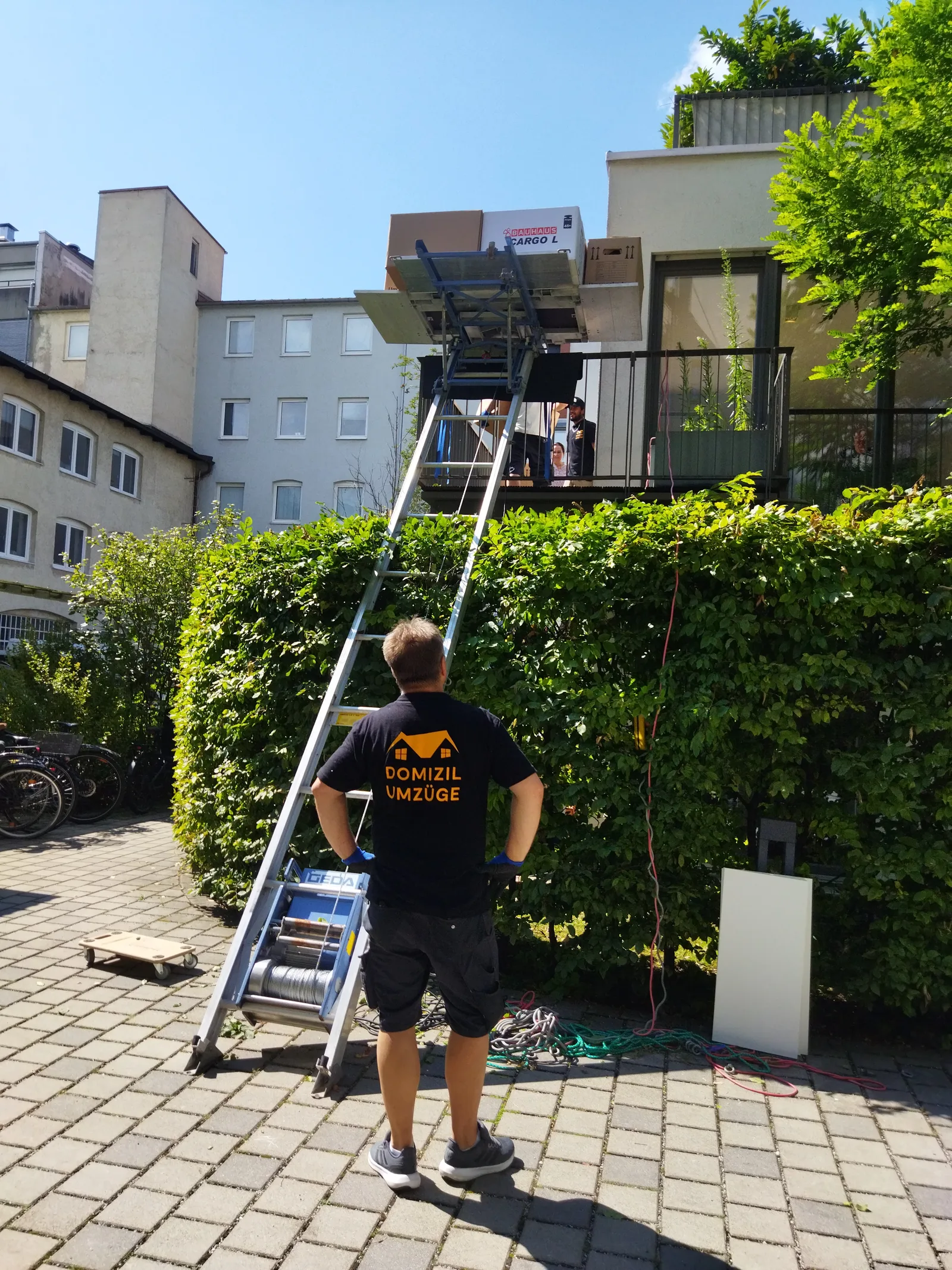 Mitarbeiter von Domizil Umzüge begleitet einen Möbellift an einem Balkon